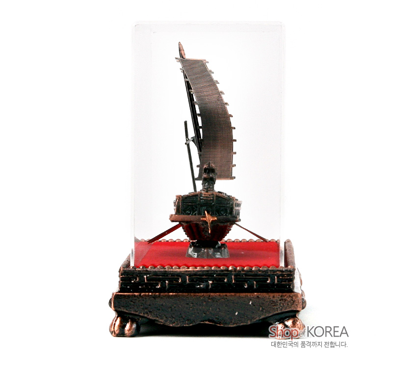 [텍스트: Shop KOREA 대한민국의 품격까지 전합니다.] 청동색 금속 재질 거북선 모형과 붉은 벨벳 바닥, 나전풍 장식무늬 받침대, 투명 아크릴 케이스 조화 이미지
