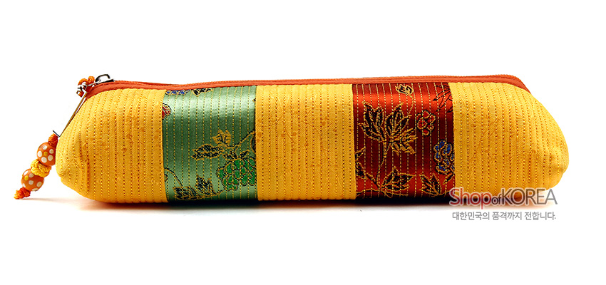 [텍스트: ShopofKOREA, 대한민국의 품격까지 전합니다.] 황색 누비 천에 녹색·적색 비단 꽃문양 띠를 더한 원통형 지퍼 필통 디자인