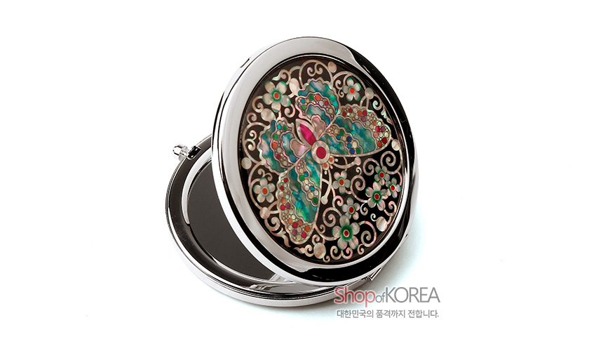 [텍스트: Shop of KOREA 대한민국의 품격까지 전합니다.] 금속 케이스에 흑색 바탕과 자개 상감 기법으로 채색 나비와 꽃문양을 섬세하게 표현한 원형 원터치 손거울 이미지 설명
