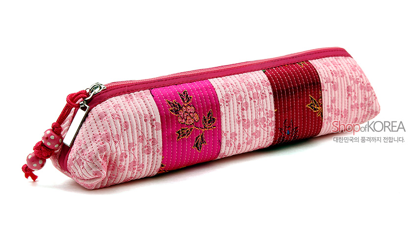[텍스트: Shop of KOREA 대한민국의 품격까지 전합니다.] 연분홍 누비 비단에 꽃무늬와 줄무늬를 배색한 원통형 지퍼 필통, 매듭 장식 태슬 포인트 디자인
