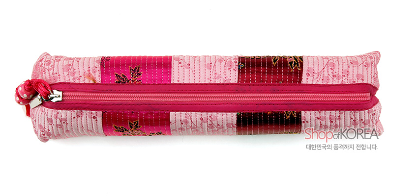 [텍스트: ShopofKOREA 대한민국의 품격까지 전합니다.] 연분홍 누비 비단 위에 꽃무늬와 줄무늬가 조합된 원통형 필통, 진분홍 지퍼와 매듭 장식 포인트 디자인