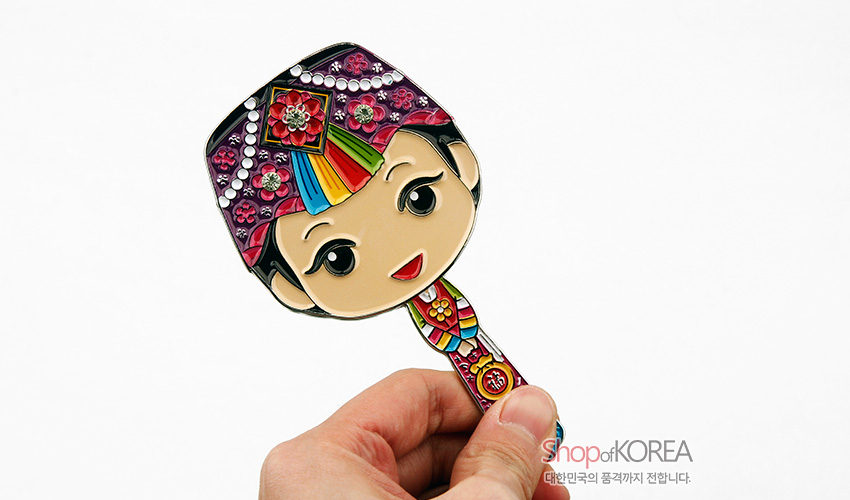 [텍스트: ShopofKOREA 대한민국의 품격까지 전합니다.] 금속 바탕에 에나멜 채색으로 표현한 색동 한복 소녀 형상 손거울, 보석 장식과 꽃·색동 문양이 화려하게 어우러진 디자인