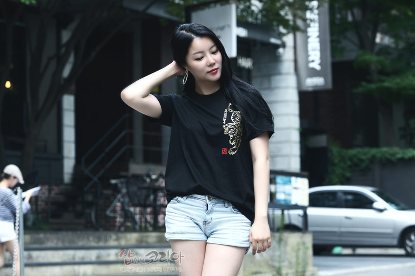 [텍스트: 샵오브코리아 대한민국 전통 문화상품 전문회사] 검정 면 티셔츠 위 금색 입체발포 호랑이 문양과 붉은 전각 스타일 낙관 포인트가 돋보이는 반소매 디자인