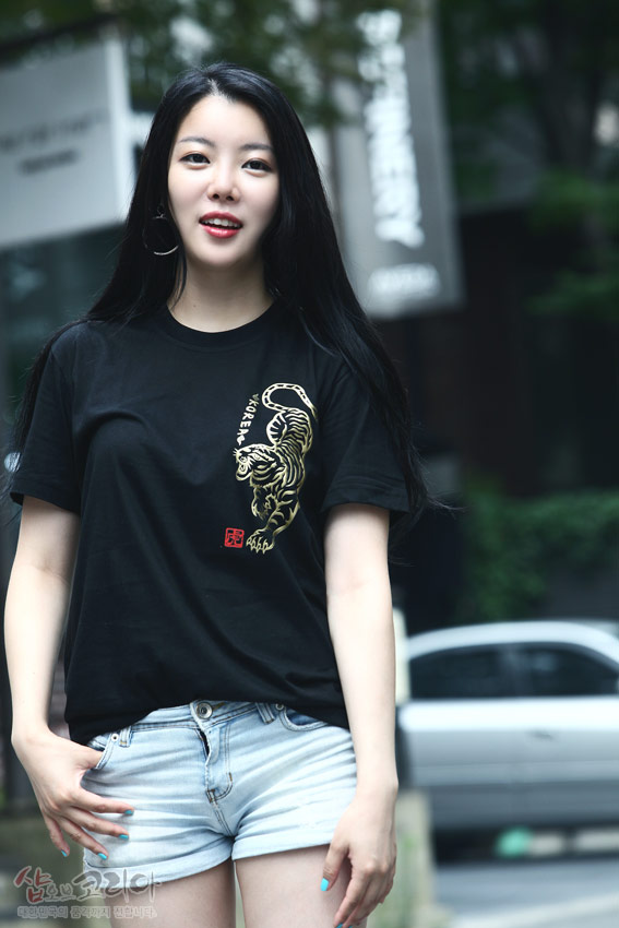 [텍스트: KOREA] 검정 면 티셔츠 위 금색 입체발포 호랑이 문양과 붉은 낙관 포인트가 대비를 이루는 반소매 티셔츠 이미지 설명