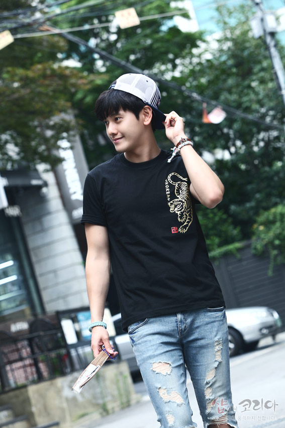 [텍스트: KOREA] 검정 면 소재 위에 금색 입체발포 기법으로 표현된 호랑이 문양과 붉은 전각 스타일 낙관이 배치된 반소매 티셔츠 연출 이미지