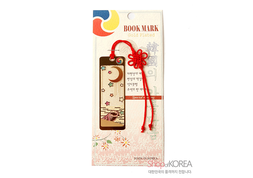 [텍스트: BOOK MARK, Gold Plated, Special meaning, MADE IN KOREA] 금장 금속 책갈피에 달과 별, 고동 문양이 양각된 직사각 디자인과 붉은 전통 매듭 끈이 조화된 모습