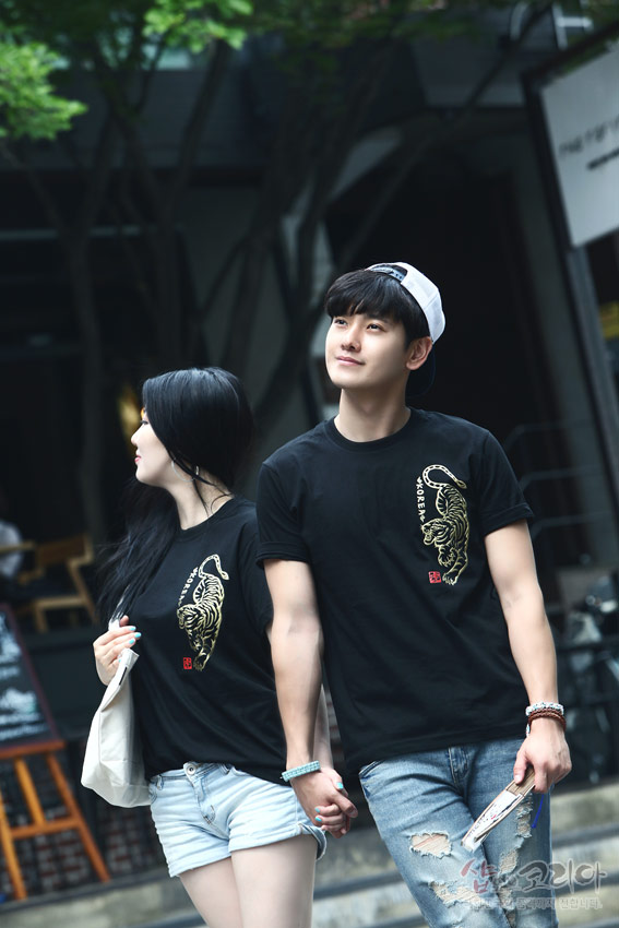 [텍스트: KOREA] 검정 면 티셔츠 위 금색 입체발포 호랑이 문양과 붉은 전각 스타일 낙관이 배치된 반팔 커플 티셔츠 연출 이미지