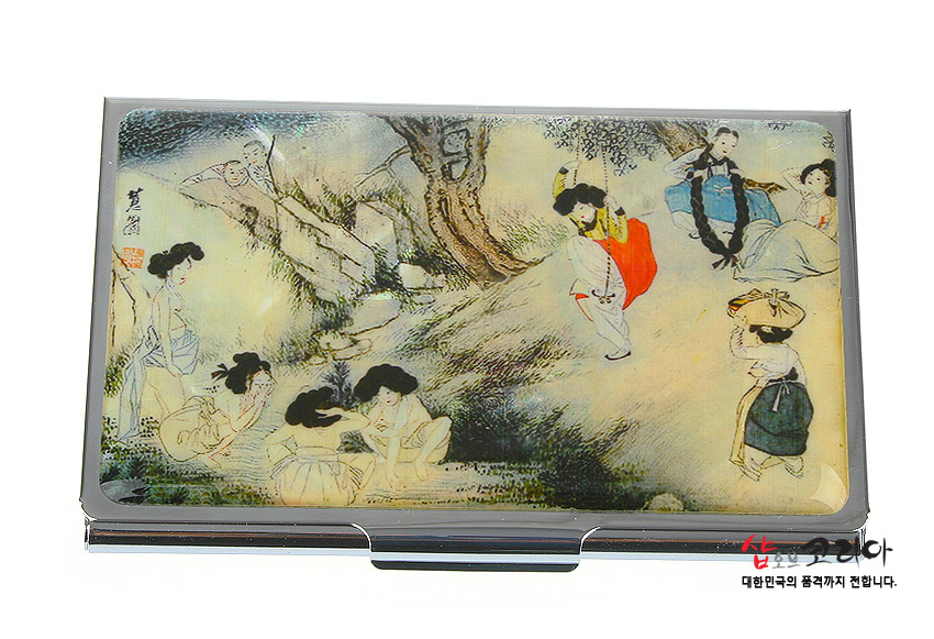 [텍스트: 샾오브코리아 대한민국의 품격까지 전합니다.] 자개 바탕 위에 섬세한 채색으로 표현된 신윤복 단오 풍속 인물화, 은은한 아이보리·청록 색조와 금속 테두리 조화가 돋보이는 직사각 명함집 디자인