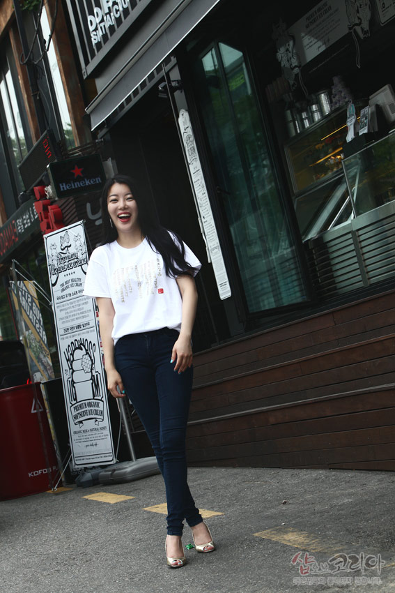 [텍스트: DD chicken / Heineken / Present by Okidoggy contemporary cake boutique] 흰색 면 티셔츠 위 금빛 입체발포 기법으로 표현된 훈민정음 한글·한자 문양 장식 모습