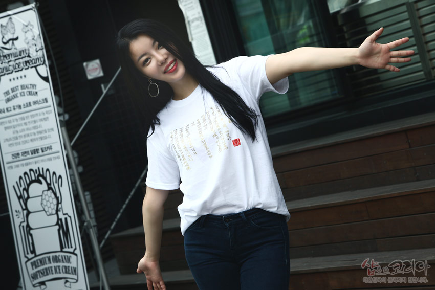 [텍스트: PREMIUM ORGANIC SOFT SERVE ICE CREAM] 흰색 면 티셔츠에 금빛 입체발포 기법으로 표현된 훈민정음 한글·한자 문양과 붉은 전각 무늬 장식 이미지 설명