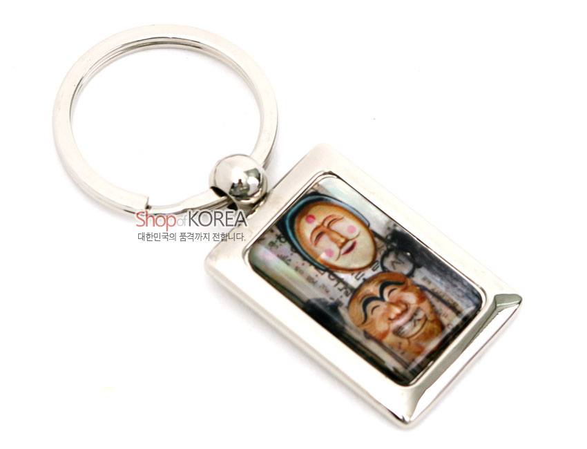 [텍스트: Shop of KOREA 대한민국의 품격까지 전합니다.] 금속 프레임 안 자개 상감 기법으로 표현된 다채로운 색감의 하회탈 문양 사각 열쇠고리 디자인
