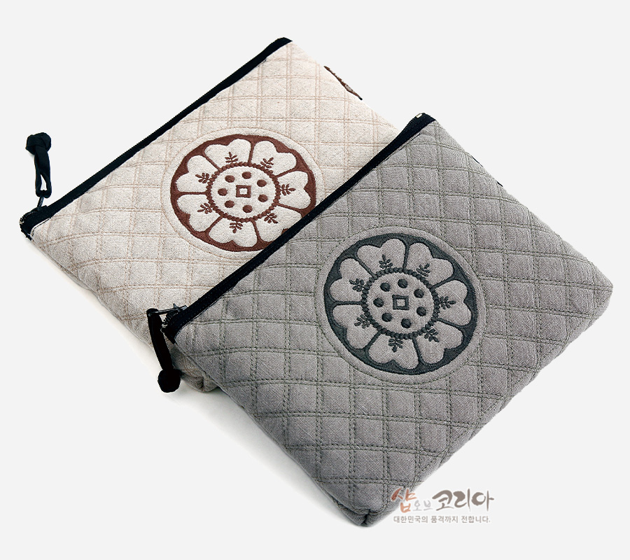[텍스트: 샵오브코리아 대한민국의 품격까지 전합니다.] 베이지와 회색 누빔 천 위에 수막새 연꽃 문양 자수를 놓은 직사각형 지퍼 파우치 디자인