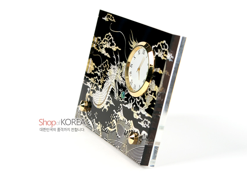 [텍스트: Shop of KOREA 대한민국의 품격까지 전합니다.] 검은 옻칠 바탕에 자개 상감으로 용·구름·파도 문양을 넣고 금색 메탈 테두리 원형 시계를 더한 탁상용 시계 디자인
