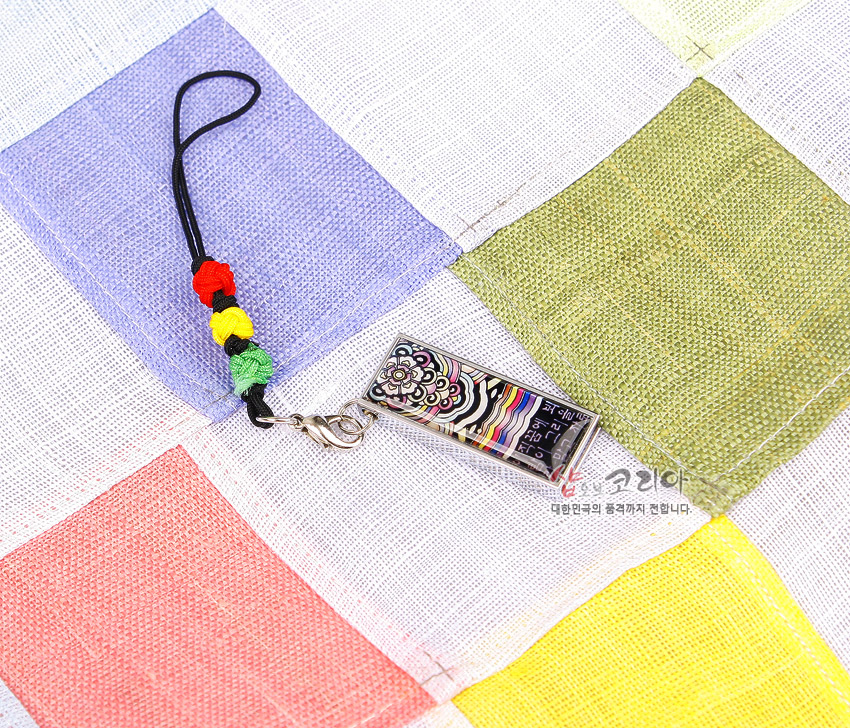 [텍스트: 샵오브코리아 대한민국의 품격까지 전합니다.] 자개 상감 기법의 금속 테두리 USB, 단청 꽃무늬와 다색 줄무늬 문양, 홍·황·녹·청 사각 조각보 배경과 오방색 매듭 스트랩 장식 이미지 설명