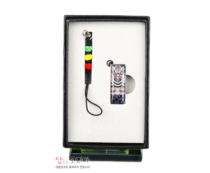 [텍스트: 샵오브코리아 대한민국의 품격까지 전합니다.] 자개 느낌의 광택 위에 시조 글귀와 단청 문양을 새긴 금속 USB, 오방색 매듭 줄과 세트 구성 이미지