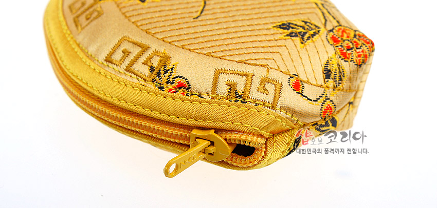 [텍스트: 샵오브코리아 대한민국의 품격까지 전합니다.] 금색 비단 누비 소재에 태극과 연속문, 꽃과 잎사귀 자수가 수놓인 반달형 지퍼 동전지갑 클로즈업 이미지