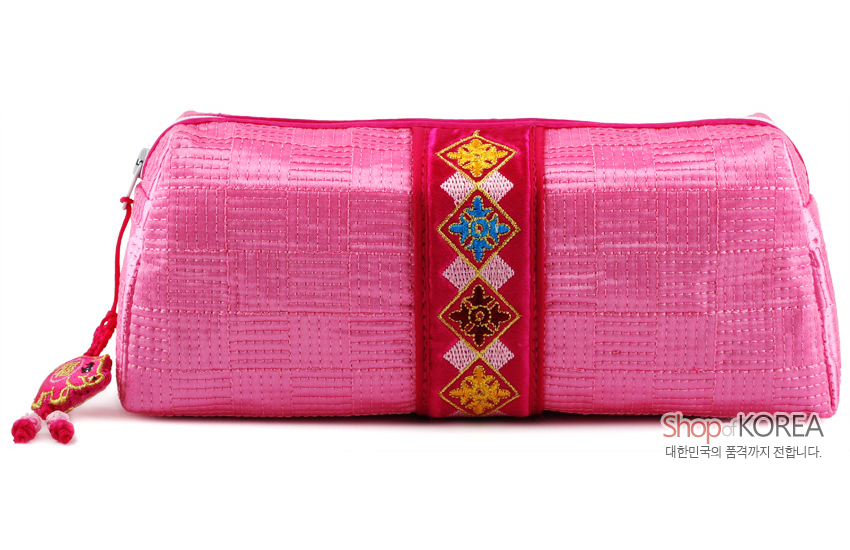 [텍스트: Shop of KOREA 대한민국의 품격까지 전합니다.] 분홍색 누비 비단 재질에 기하학 누빔무늬와 중앙 색실 전통문양 자수 띠, 끝부분 복돼지 매듭 장식 필통형 파우치 모습