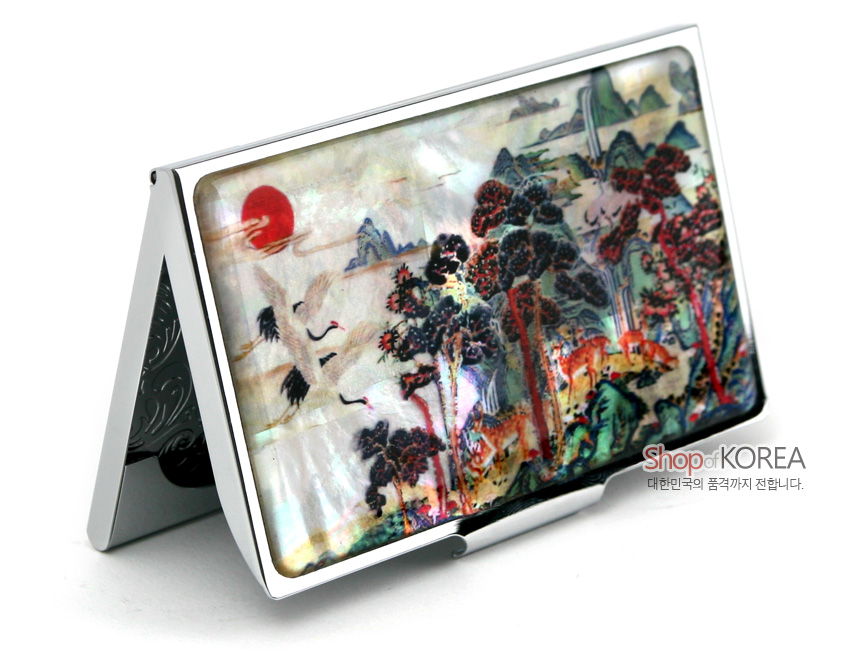 [텍스트: Shop of KOREA 대한민국의 품격까지 전합니다.] 자개 상감 기법으로 표현한 십장생 산수와 학·소나무 문양이 다채로운 색감으로 장식된 금속 명함집 이미지 설명