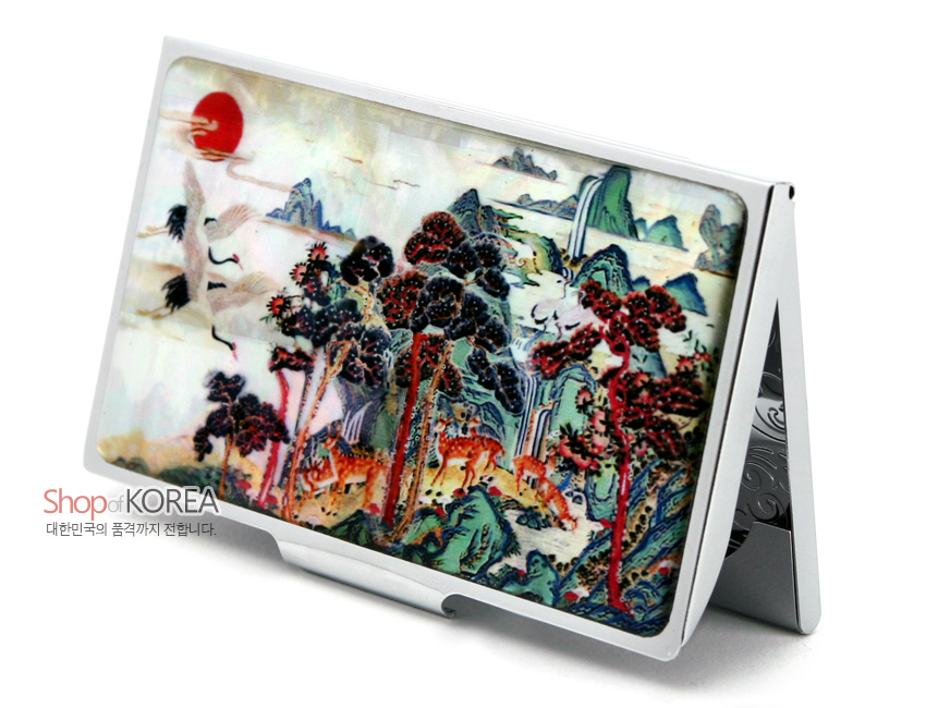 [텍스트: Shop of KOREA 대한민국의 품격까지 전합니다.] 자개 상감 기법으로 표현한 십장생 민화 문양과 붉은 해·학·사슴·소나무가 어우러진 다채로운 색감의 금속 명함집 이미지 설명