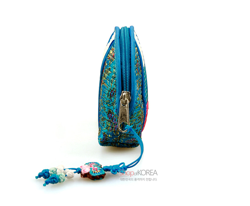 [텍스트: ShopofKOREA 대한민국의 품격까지 전합니다.] 청색 누비 비단에 전통 꽃문양이 수놓인 동전지갑 측면, 금속 지퍼와 색실 매듭 노리개 장식 모습