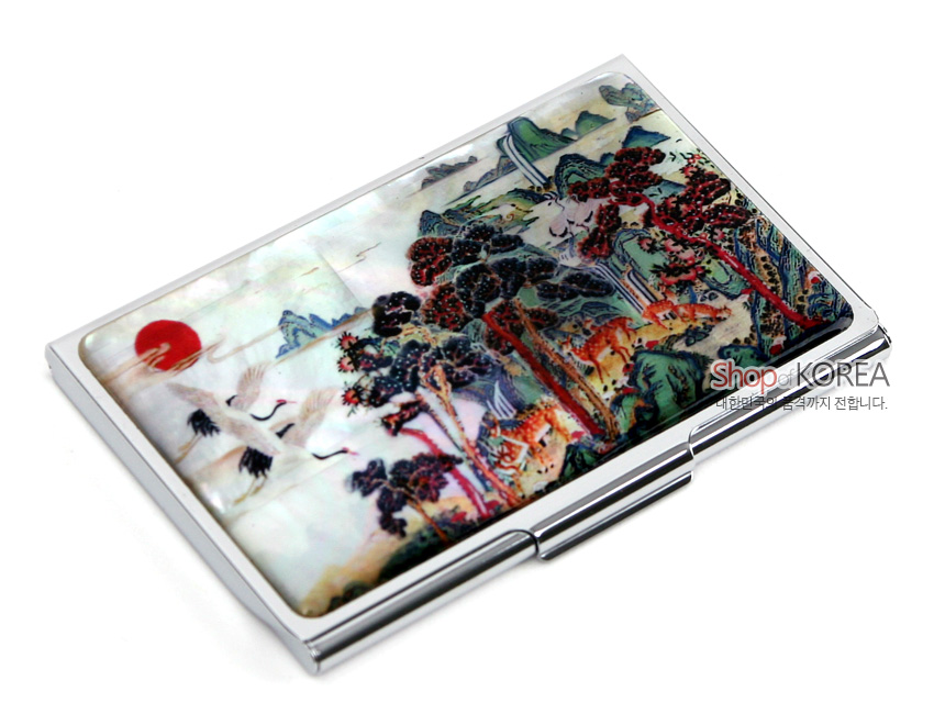 [텍스트: Shop KOREA 대한민국의 품격, 세계까지 전합니다.] 자개 상감 기법으로 표현한 십장생 민화 산수와 해·학·소나무, 사슴 문양이 다채로운 색감으로 장식된 금속 명함집 디자인
