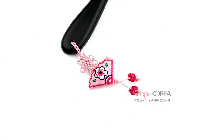 [텍스트: Shop of KOREA 대한민국의 품격까지 전합니다.] 검은색 매끈한 손잡이에 분홍색 비단 조개 매듭과 꽃 자수 장식 주머니가 어우러진 전통 손거울 디테일 컷 이미지 설명