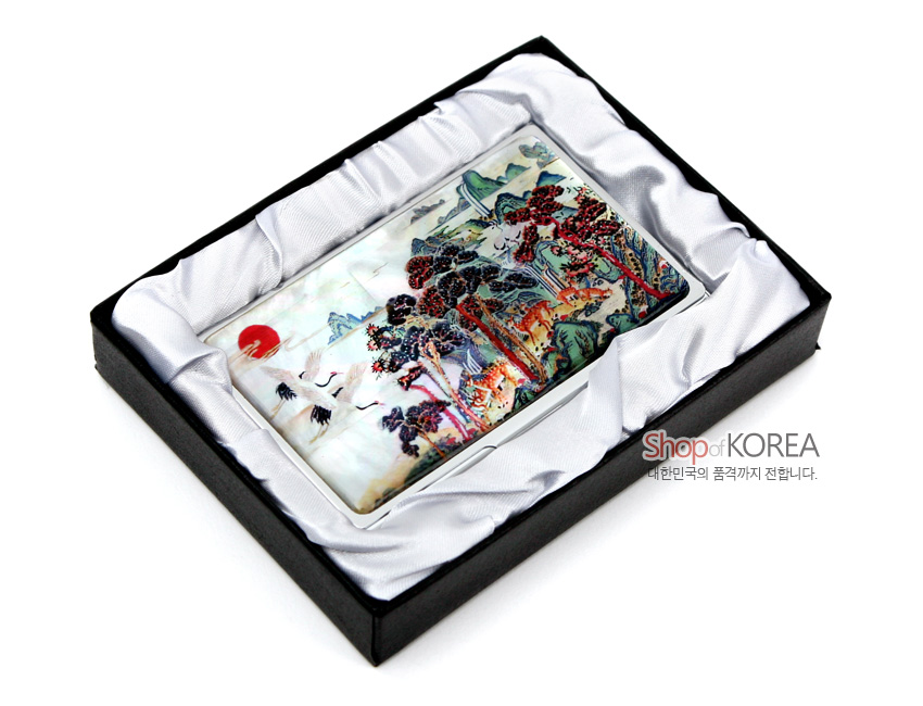 [텍스트: Shop of KOREA / 대한민국의 품격까지 전합니다.] 자개 상감 기법으로 십장생 민화 산수와 해·학·소나무를 다채로운 색감으로 표현한 금속 명함집 이미지 설명