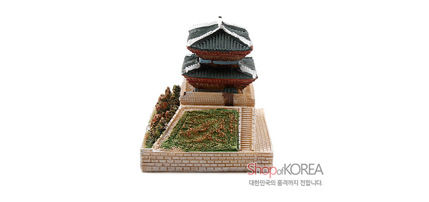 [텍스트: ShopofKOREA 대한민국의 품격까지 전합니다.] 석고 재질의 남대문 모형, 녹색 기와지붕과 연갈색 성곽 벽돌 문양, 입체적으로 표현된 수풀과 잔디밭 장식 구성
