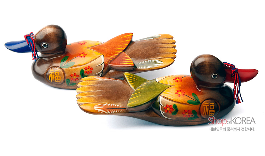 [텍스트: 福, Shop of KOREA, 대한민국의 품격까지 전합니다.] 원목 재질에 채색 기법을 더한 꽃무늬 원앙 한 쌍 목각 장식, 복자 문양과 붉은 실 매듭, 주황·노랑·파랑 대비 색감이 돋보이는 디자인