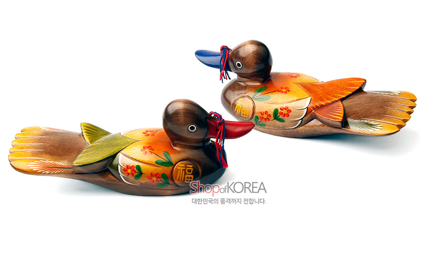 [텍스트: ShopofKOREA 대한민국의 품격까지 전합니다.] 나무 재질 위 채색 기법, 붉은·푸른 부리와 실매듭 장식, 꽃무늬와 복(福)자 문양이 더해진 원앙 한 쌍 목각 장식품