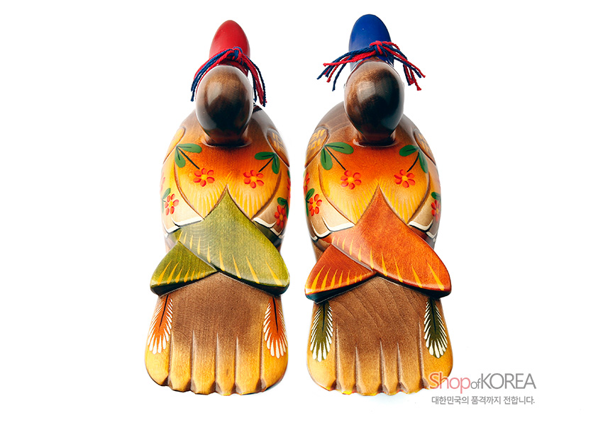 [텍스트: ShopofKOREA 대한민국의 품격까지 전합니다.] 원목 재질에 채색 기법을 더한 꽃·잎사귀 문양의 원앙 한 쌍, 붉은색·푸른색 머리와 실끈 장식이 돋보이는 목각 장식품