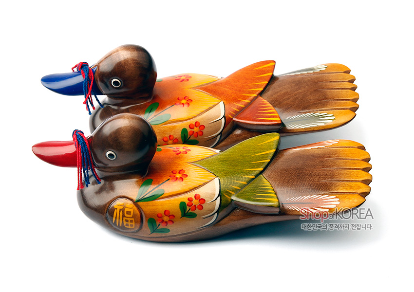 [텍스트: 福, Shop of KOREA, 대한민국의 품격까지 전합니다.] 나무 재질에 채색 기법으로 표현된 원앙 한 쌍 목각 장식, 복자와 꽃무늬 문양, 붉은·푸른 부리와 실 매듭 장식, 갈색과 노랑·초록 색상의 조화가 돋보이는 인테리어 장식품