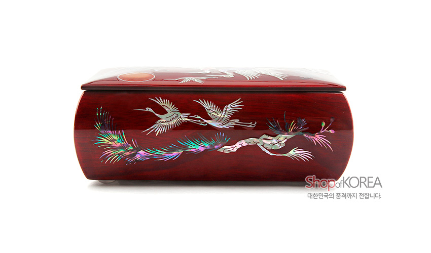 [텍스트: ShopofKOREA 대한민국의 품격까지 전합니다.] 붉은 옻칠 바탕 위에 자개 상감 기법으로 송학과 소나무를 섬세하게 표현한 곡선형 반지꽂이 함 디자인