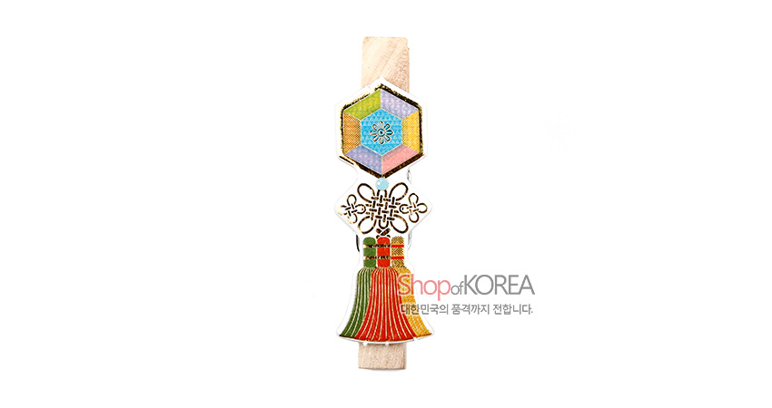 [텍스트: ShopofKOREA 대한민국의 품격까지 전합니다.] 육각 전통 문양과 금속 매듭 장식, 다채로운 색실의 버선 모양 장신구가 더해진 나무 메모자석 집게 디자인
