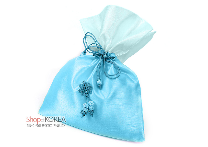 [텍스트: Shop of KOREA 대한민국의 품격까지 전합니다.] 연한 청벽색 비단 소재의 광택 있는 복주머니로, 반투명 상단과 한국 전통 매듭 및 꽃 장식 술이 조화를 이룬 디자인