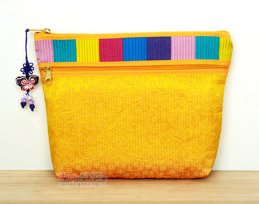 [텍스트: Shop of KOREA 대한민국의 품격까지 전달합니다] 황색 누비 원단에 섬세한 퀼팅 문양, 상단 분홍·청록·적·보라 등 색동 배색, 금속 지퍼와 나비 전통 매듭 장식이 어우러진 파우치 지갑 이미지 설명