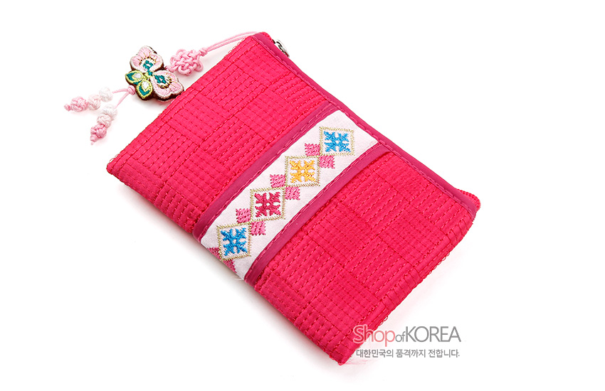 [텍스트: Shop of KOREA 대한민국의 품격까지 전달합니다.] 분홍색 누비 비단 재질에 중앙 오방색 전통 기하학 자수 띠와 나비 매듭 장식이 돋보이는 사각 동전지갑 디자인