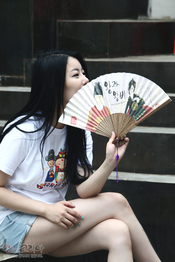 [텍스트: KOREA] 흰색 면 티셔츠 위에 한복 입은 신랑신부 캐릭터와 태극 문양, 컬러풀한 3D 입체발포 프린트가 돋보이는 디자인