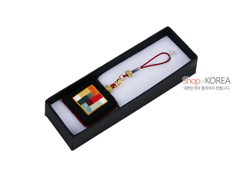 [텍스트: Shop of KOREA 대한민국의 품격까지 전합니다.] 검정 비단 바탕에 다채로운 색상의 조각보 누비 문양을 넣고 금속 장식과 붉은 끈으로 마감한 사각 거울 열쇠고리 이미지 설명