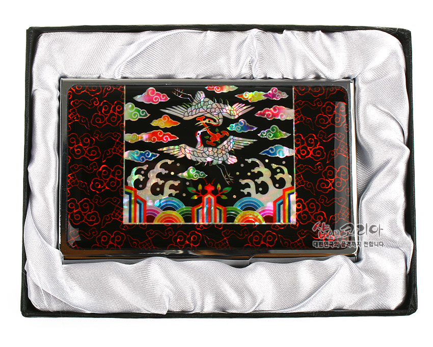 [텍스트: 샵오브코리아 대한민국의 품격까지 전합니다.] 흑색 금속 명함집 위에 자개 상감 기법으로 흉배의 쌍학과 오봉, 오색 운문과 파도, 단청색 무지개 문양을 화려하게 배치한 디자인