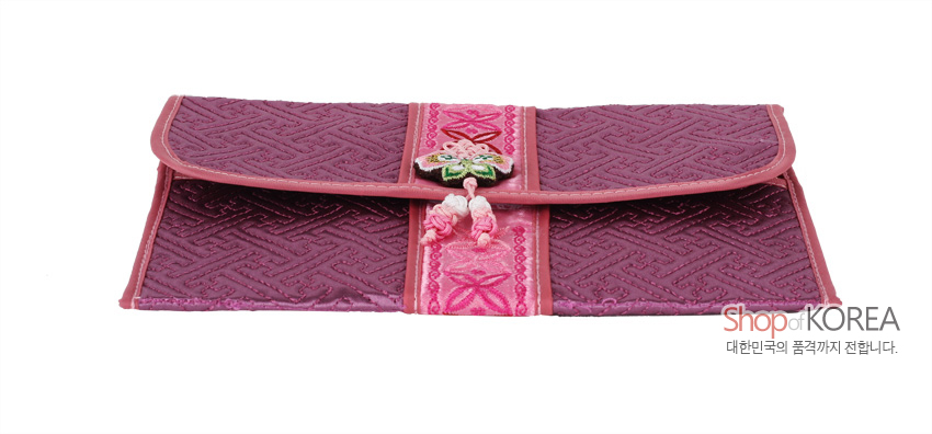 [텍스트: Shop of KOREA, 대한민국의 품격까지 전합니다.] 자주색 누비 원단에 기하학 문양을 넣고, 중앙 분홍색 띠에 꽃자수와 전통 매듭 장식이 더해진 직사각형 여권·통장 지갑 모습