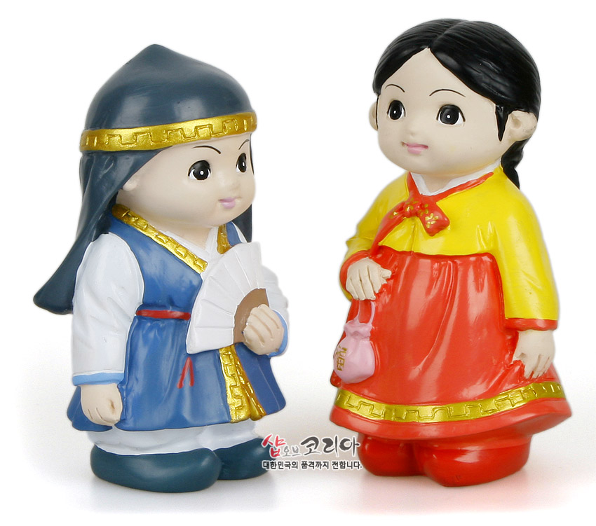 [텍스트: 샵오브코리아 대한민국의 품격까지 전합니다.] 알록달록 채색 플라스틱 재질의 춘향·몽룡 한복 인형, 금색 선과 띠 장식, 부채와 조그만 주머니 디테일이 돋보이는 디자인
