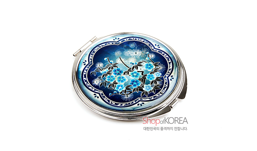 [텍스트: Shop of KOREA 대한민국의 품격까지 전합니다.] 청색 그라데이션 바탕에 자개 상감 기법으로 매화와 민들레 문양을 섬세하게 표현한 원형 금속 손거울 디자인