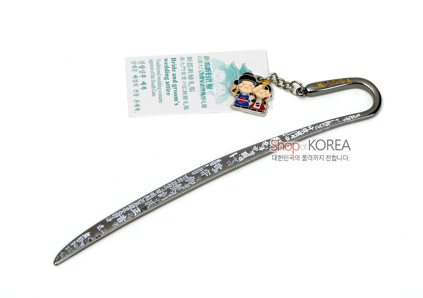 [텍스트: Shop OF KOREA, Bride and groom’s Wedding attire, KOREA] 한글 문양이 흰색으로 새겨진 은빛 금속 책갈피와 한복 입은 신랑신부 캐릭터 에나멜 장식 구성