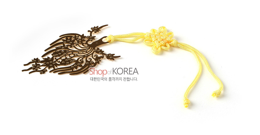 [텍스트: Shop of KOREA 대한민국의 품격까지 전합니다.] 금속 재질 금장 왕관 장식과 식물문양 레이저 절삭, 노란색 전통 매듭 끈이 어우러진 책갈피 디자인