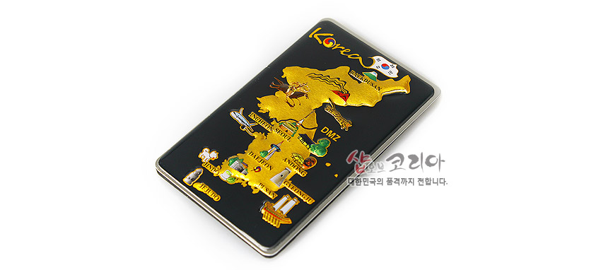 [텍스트: Korea, DMZ, BUSAN, JEJU ISLAND, GWANGJU, KOREA SHOP 대한민국의 품격까지 전합니다.] 검은 바탕 위 금속 재질 직사각형 판에 금색 입체 한반도 지도와 주요 도시 관광 아이콘이 배치된 메모홀더 디자인