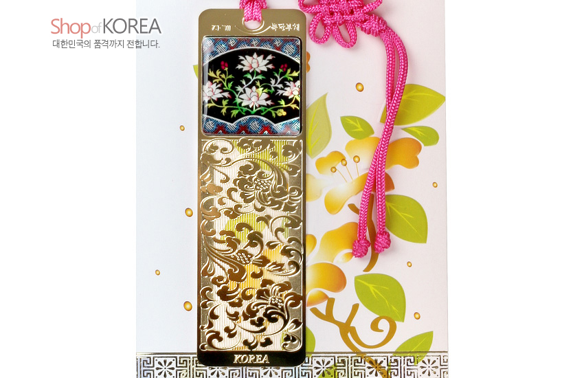 [텍스트: Shop of KOREA, 대한민국의 품격까지 전합니다., 자개 책갈피, KOREA] 흑색 바탕 자개 상감 목단과 파도 무늬, 금색 금속 투각 부채 문양, 분홍 전통 매듭 장식 책갈피 이미지 묘사