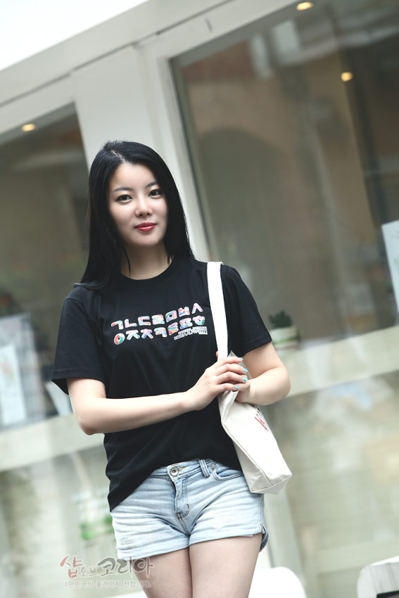 [텍스트: ㄱㄴㄷㄹㅁㅂㅅ ㅇㅈㅊㅋㅌㅍㅎ] 검정색 면 소재 위에 형형색색 한글 자음을 가로로 배치한 3D 입체발포 프린트 반팔 티셔츠 착용 모습