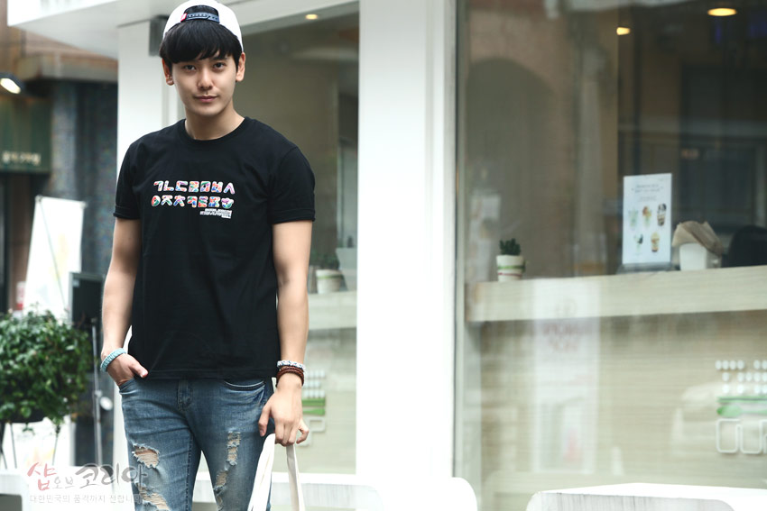 [텍스트: ㄱㄴㄷㄹㅁㅂㅅ ㅇㅈㅊㅋㅌㅍㅎ] 흑색 면 소재 위에 한글 자음을 가로로 배열한 3D 입체발포 프린트가 강조된 반팔 티셔츠 모습