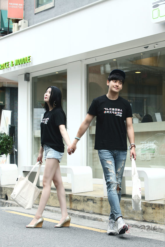 [텍스트: ㄱㄴㄷㄹㅁㅂㅅ ㅇㅈㅊㅋㅌㅍㅎ] 검정색 면 반팔 티셔츠에 흰색과 컬러 포인트의 한글 자음 가로 배열 3D 입체발포 프린트가 적용된 캐주얼 거리 패션 연출